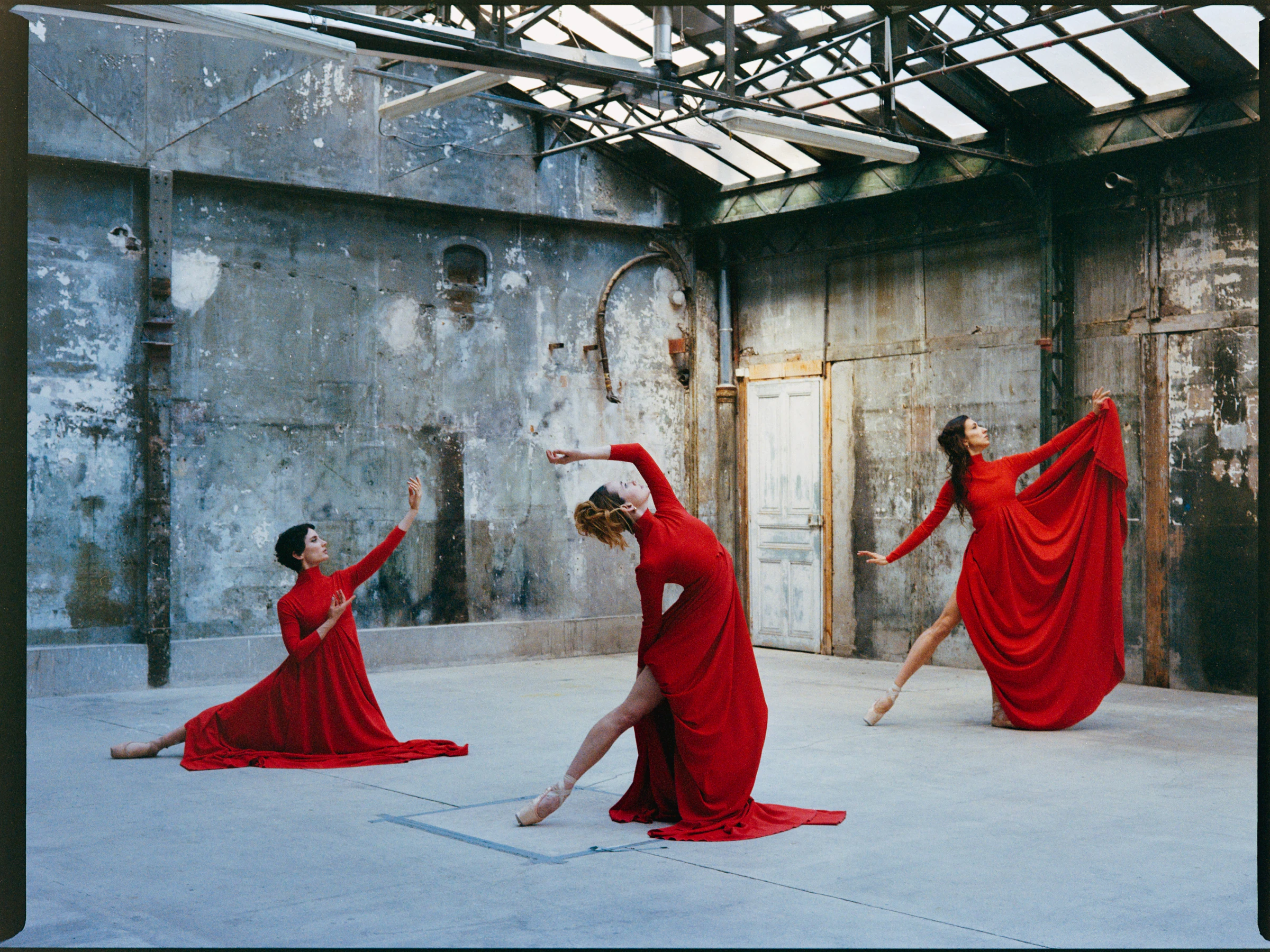 Three figures in red dresses in motion